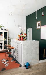 Jean-Christophe Aumas’ multihued Paris apartment houses both the highly sought artistic director and the stunning assemblage of furniture he’s brought back from his travels. Aumas designed the kitchen island, which is covered in marble tiles from Carrelages du Marais—the geometric floor tiles are from the same place—and strung the matrix of lights up above it. The barstools by Charlotte Perriand were discovered in a vintage store in Antwerp, Belgium. The green wall is covered in paint from Emery & Cie.