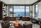 The office features a nearly full-width picture window in front of built-in desks. Views extend beyond the immediate cove to the Atlantic Ocean and horizon.